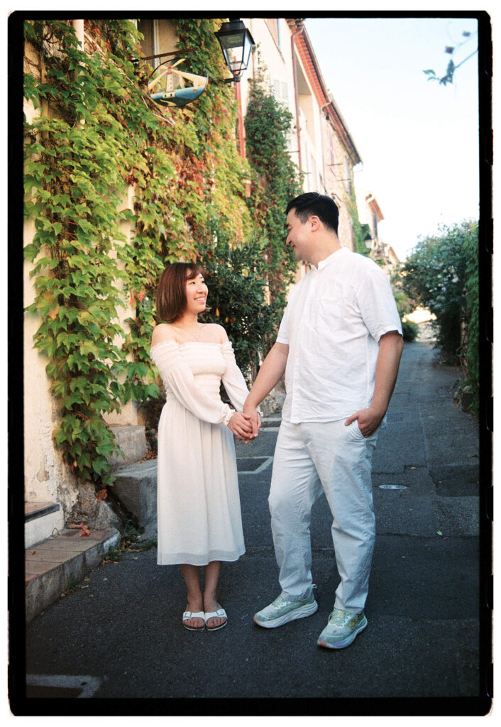 Honeymoon couple holding hands in a small alley in Antibes surrounded by old French houses and ivy