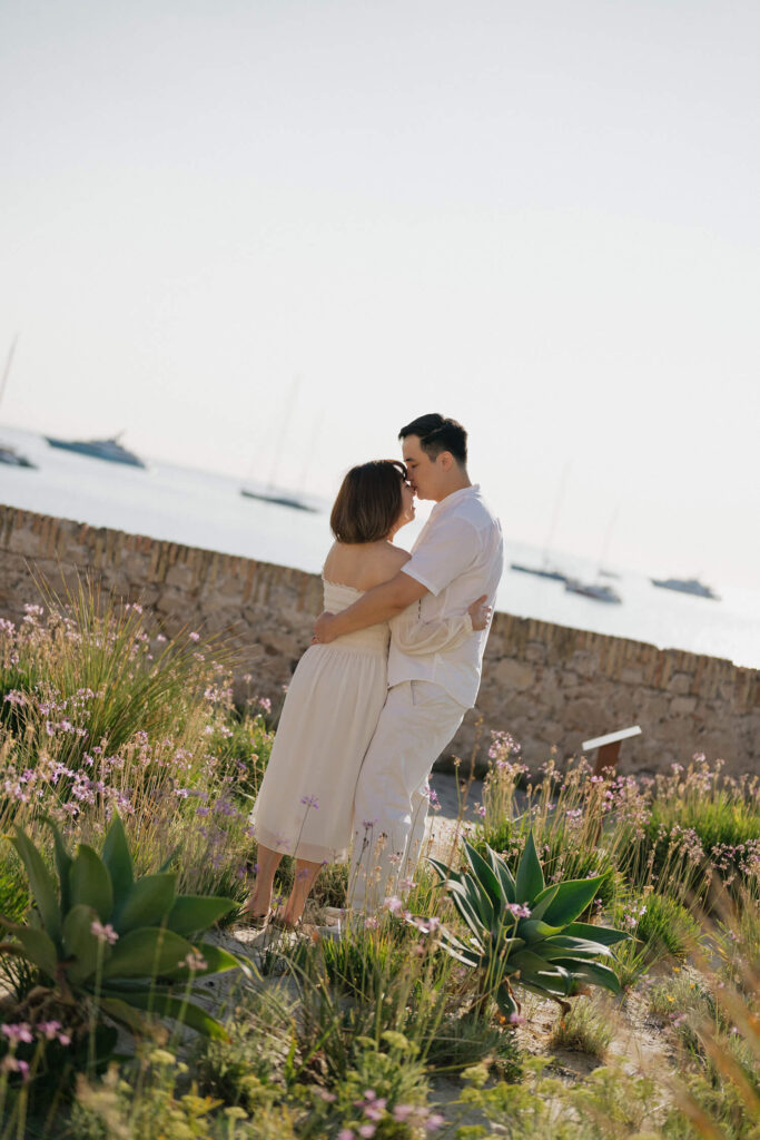 Honeymoon couple standing in a garden overlooking the sea and boats in Antibes on the French Riviera